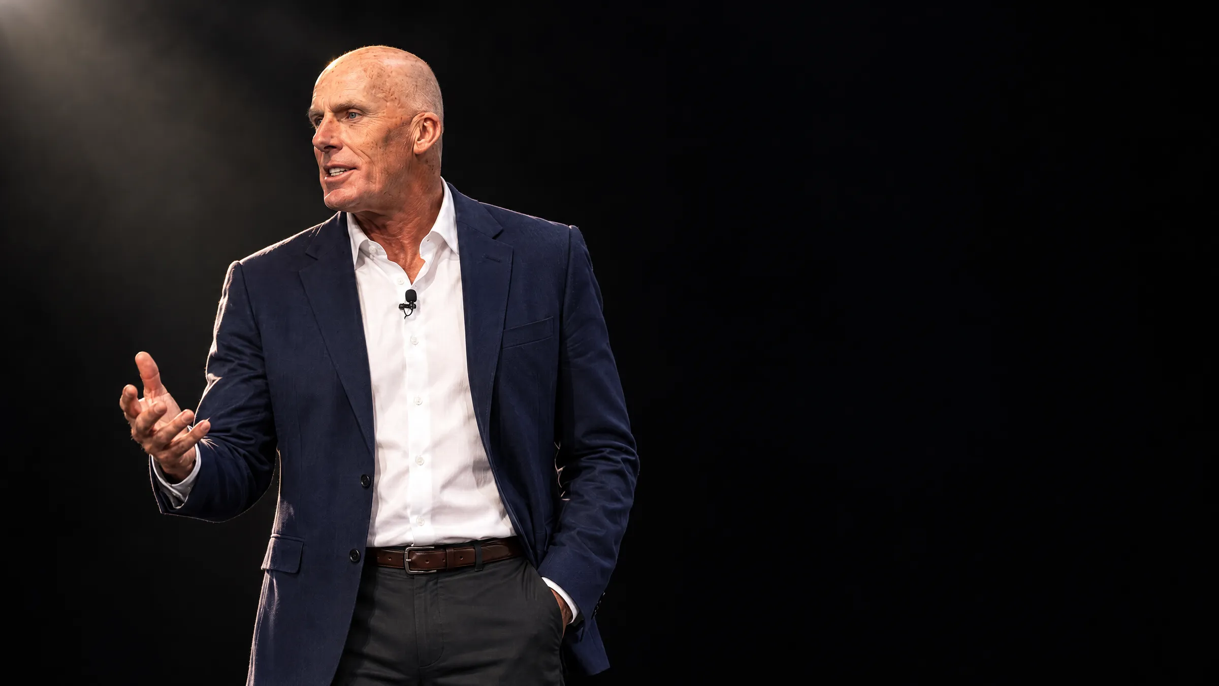Mark McKeon on a dark conference stage in black and white